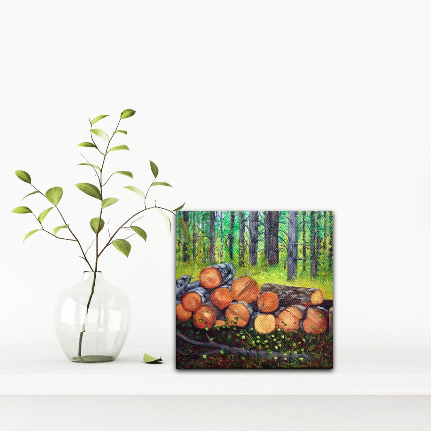 Woodpile is a small 6x6 oil painting of a forest with cut trees on a counter beside a plant