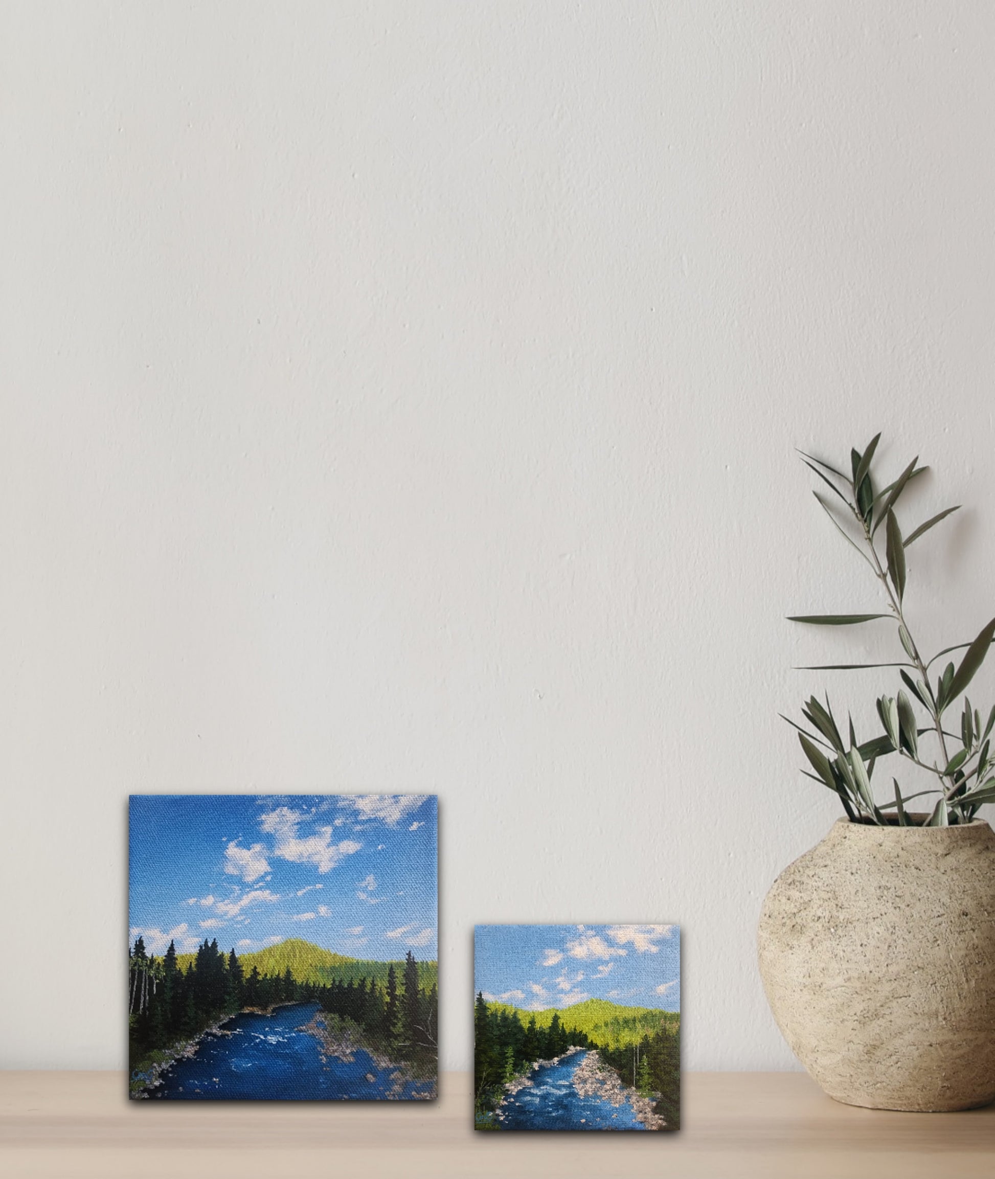 two small 6 inch by 6 inch and 4 by 4 inch oil paintings of a river surrounded by trees and miles of forest.