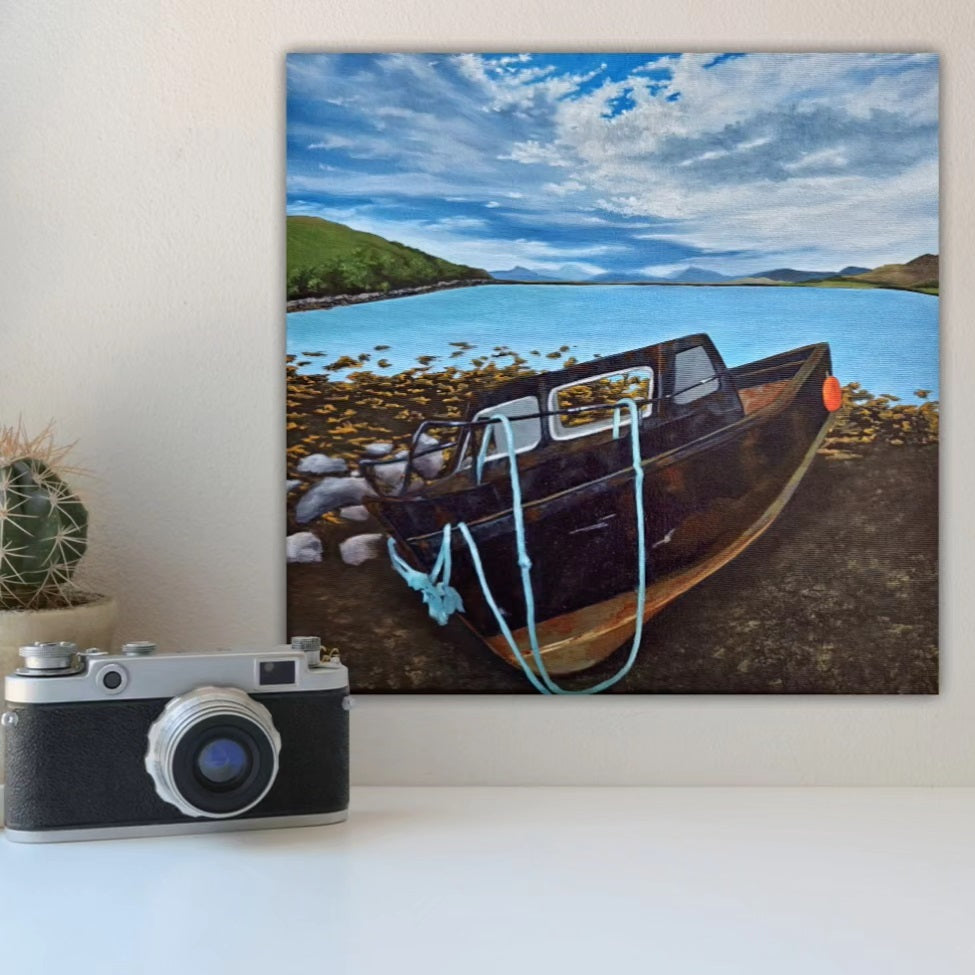 Christina Gouldsborough Canadian Landscape Artist - Beached - An original oil landscape painting of a boat beached on low tide, with a dramatic display of clouds in the sky, hanging on a wall behind a camera and cactus