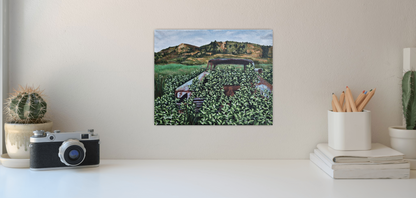 painting of vintage car on wall behind desk with camera , plant and stationary