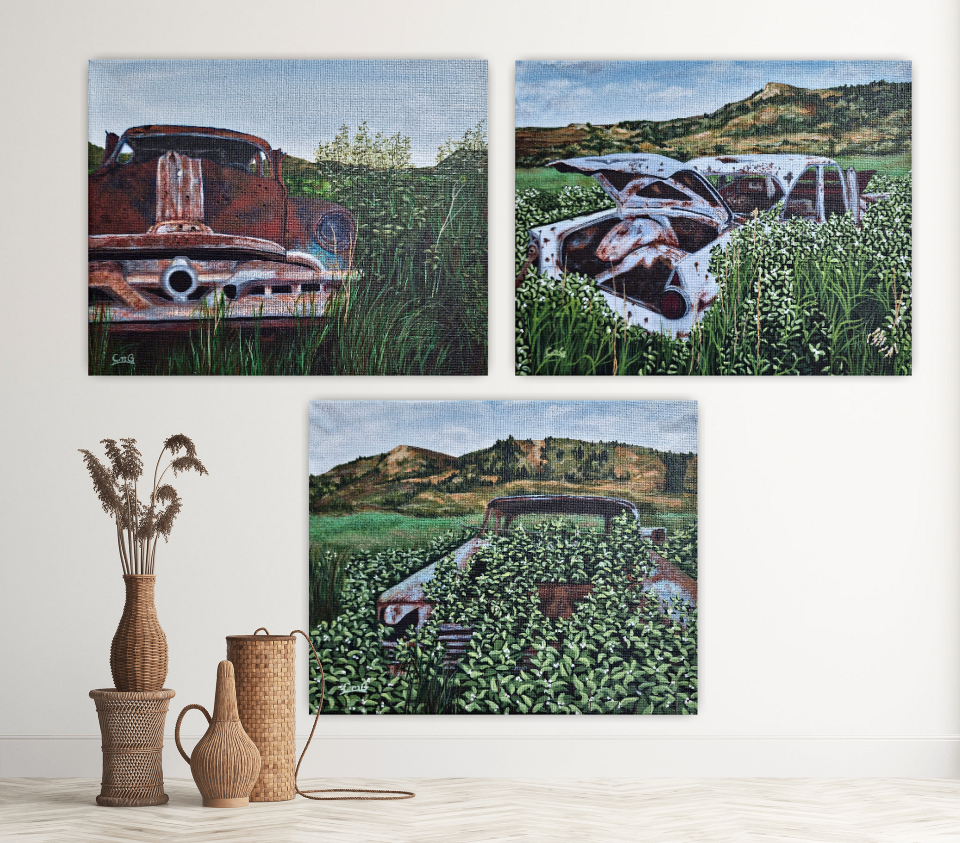 Three acrylic paintings of abandoned cars in the badlands on a wall behind wicker home decor