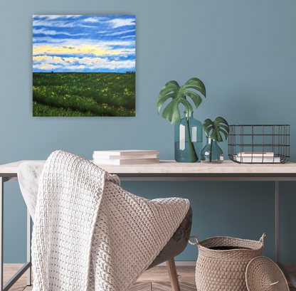 After the Rain Canadian landscape painting of a summer canola field after a rain storm by Christina Gouldsborough on a blue wall behind a wood desk and chair with throw